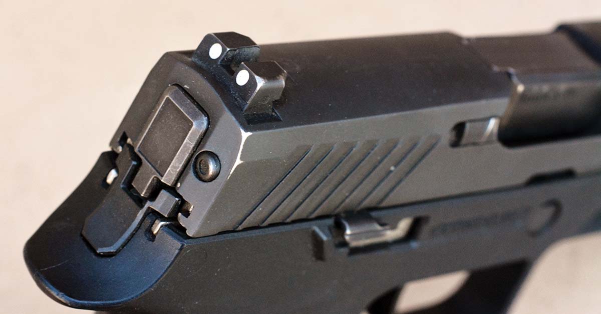 The rear sight features two white dots and is dovetailed into the slide.
